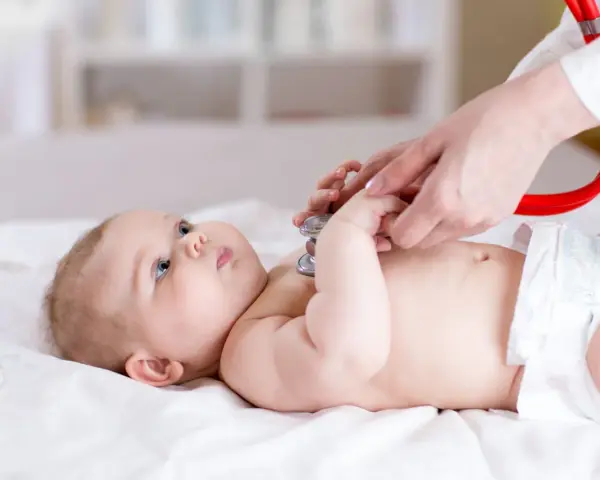 Lekarz osłuchuje niemowlę stetoskopem. Badanie może pomóc w wykryciu chorób metabolicznych u dzieci, lista schorzeń jest długa.
