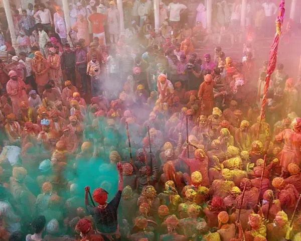 Tłum ludzi w kolorowym pyle podczas festiwalu Holi. To jedno z wielu barwnych festiwali na świecie, pełne radości i tradycji.