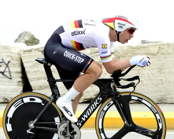 Cyclist in full aerodynamic gear, focused on time trial training, pushing hard on a specialized bike.
