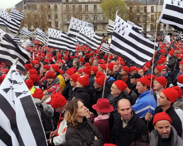 Foule portant le bonnet rouge breton, brandissant des drapeaux bretons.