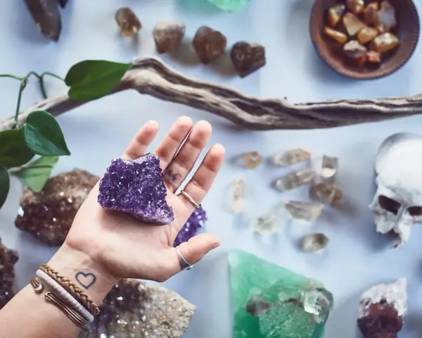 Mano sostiene amatista, rodeada de piedras y un cráneo. Un conjunto de piedras contra el mal de ojo y la envidia.