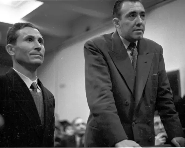 Deux hommes en costume, dont Gustave Dominici, se tiennent debout dans une salle.