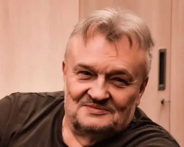 Uśmiechnięty Krzysztof Cugowski, z siwiejącymi włosami i zarostem. Zastanawiasz się, ile lat ma Krzysztof Cugowski?