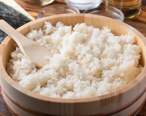 Idealny ryż do sushi, gotowy do przygotowania. Drewniana miska i łyżka sugerują tradycyjny sposób na to, jak ugotować ryż do sushi.