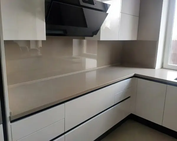 Nowoczesna kuchnia z frontami w kolorze ral9001 i eleganckim, jasnym blatem. Czarny okap dodaje charakteru.