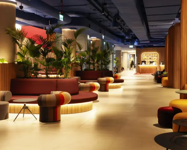 Nowoczesne wnętrze z roślinnością i kolorowymi meblami. Recepcja hotelu Mercure Warszawa Centrum wita gości.