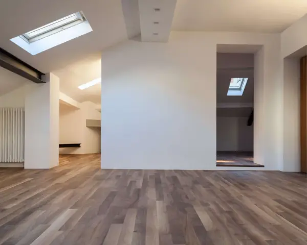 Interno moderno con pavimenti in legno e pareti in cartongesso sottotetto. Finestre sul tetto illuminano lo spazio.