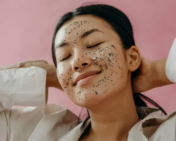 A woman with a sparkly exfoliating mask on her face, enjoying a moment of self-care. Over-exfoliation can sometimes lead to breakouts, so it's important to find the right balance.