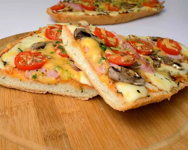 Dwie pyszne pizze na bagietce z pomidorami, pieczarkami i serem. Idealne na szybki obiad.