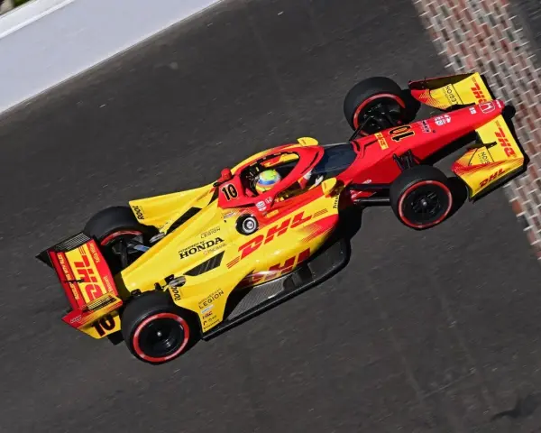 Alex Palou, piloto del coche número 10, acelera en la pista con su monoplaza amarillo y rojo de DHL.