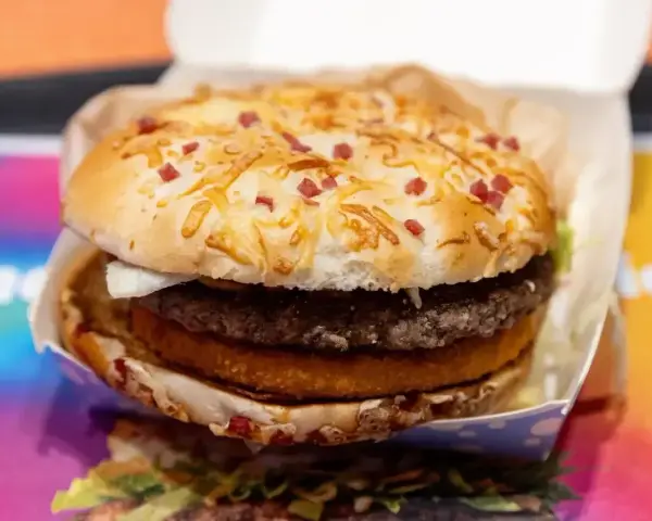 Pyszny burger drwala z podwójnym mięsem, chrupiącym plackiem ziemniaczanym i bułką posypaną serem i kawałkami boczku.