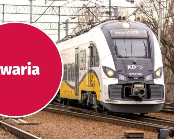 Pociąg KD stoi na torach, a czerwone koło z napisem "Awaria" sugeruje problem z zasilaniem, być może zerwana sieć trakcyjna.