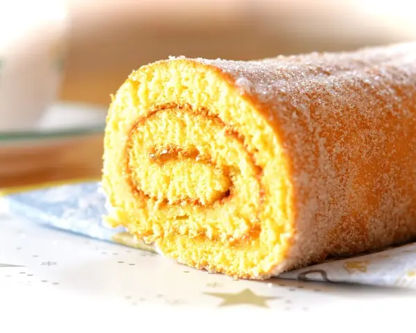 En saftig glutenfri rulltårta med socker strött över, perfekt för fikat.