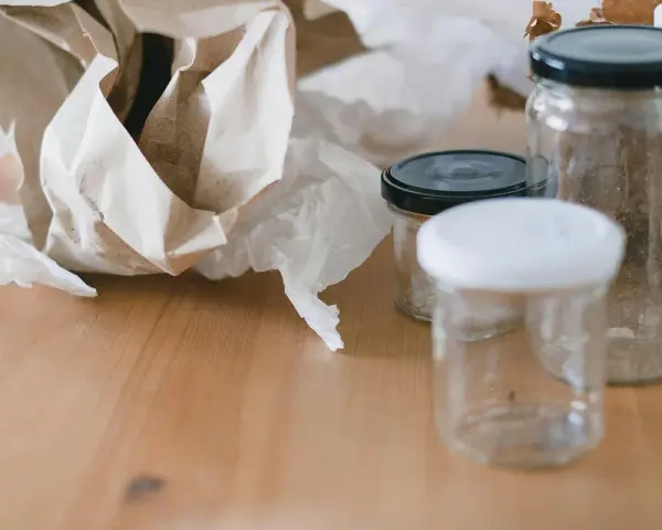 Puste słoiki i pogniecione papierki na drewnianym stole. Zastanawiasz się, gdzie wyrzucać nakrętki od słoików?