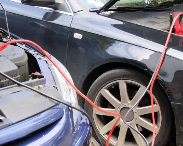 Zwei Autos werden mit Starthilfekabeln verbunden, um die Batterie zu starten.