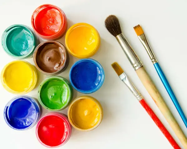 Tarros de temperas de colores vibrantes y pinceles listos para pintar.
