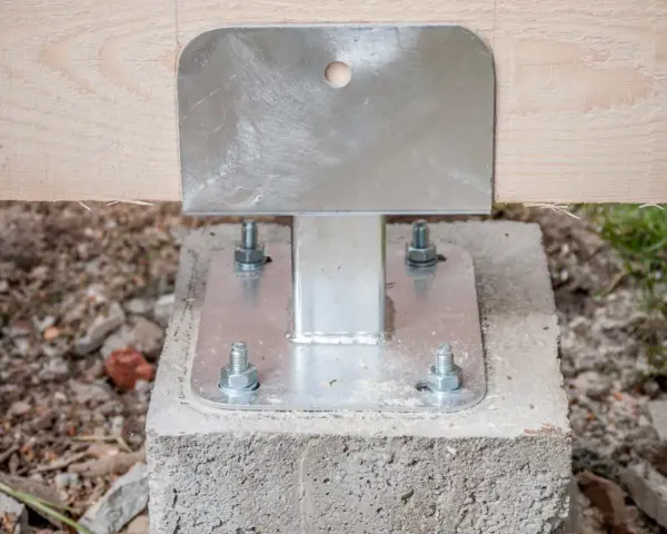 Pied de poteau métallique fixé sur un plot béton à enterrer, soutenant une poutre en bois.