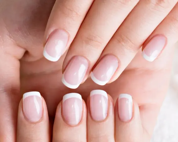 Dłonie z idealnym french manicure, gdzie białe końcówki paznokci lśnią jak tytanowe paznokcie.