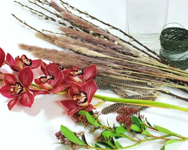 Ciemnoróżowe orchidee, trawy, pióra i gałązki tworzą kompozycję zrównoważoną.
