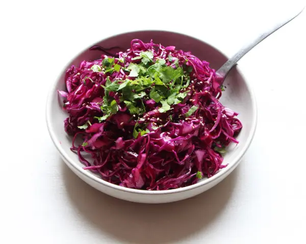 Salade colorée de chou rouge râpé, garnie de coriandre fraîche et de graines de sésame. Une idée simple pour une recette chou rouge savoureuse.