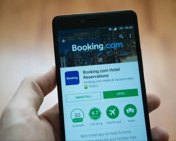 Telefon z aplikacją Booking.com. Użytkownik przegląda szczegóły, być może w celu zgłoszenia booking reklamacja.