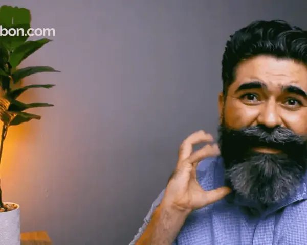 Hombre con una barba corta y cuadrada, peinada con estilo. A su lado, una planta y productos de cuidado personal.