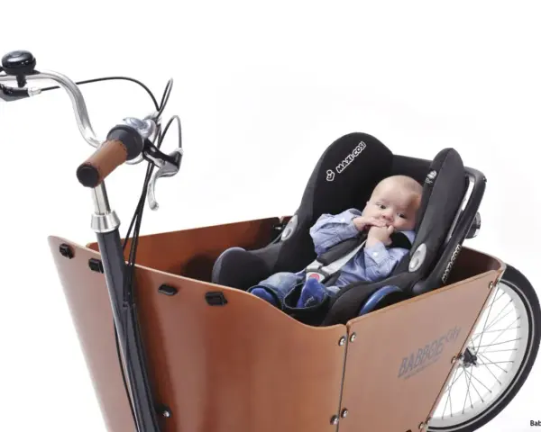 En bebis sitter tryggt i en bilbarnstol monterad i en lastcykel. Perfekt för att cykla med bebis på ett säkert och bekvämt sätt.