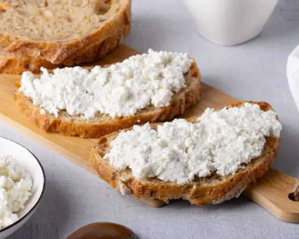 Fette di pane rustico con abbondante ricotta fresca, pronte per gustose ricette con ricotta.