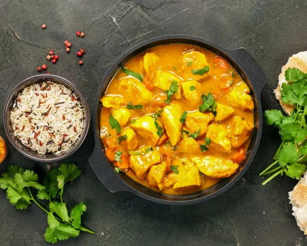 Kurczak w sosie curry z ryżem, kolendrą i pieczywem.