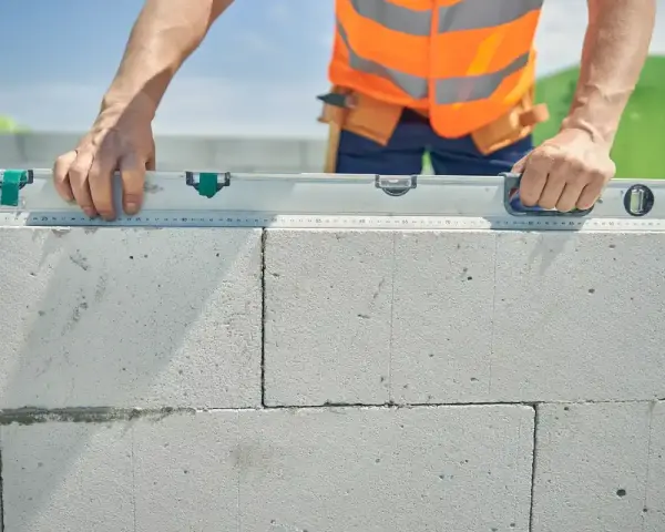 Un maçon vérifie le niveau d'une rangée de parpaings. Il se demande combien de rangée de parpaing par jour il peut poser.