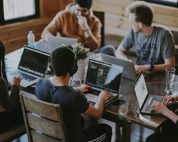 Un grupo de personas trabaja en sus portátiles en una mesa. Uno de ellos, con auriculares, parece concentrado en su pantalla, quizás buscando la clave del modelo 190.