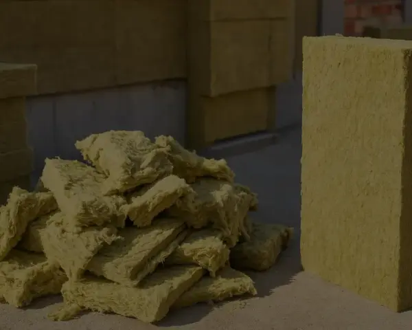 Stos wełny mineralnej i pojedynczy blok, gotowe do utylizacji. Materiał izolacyjny czeka na właściwe zagospodarowanie.