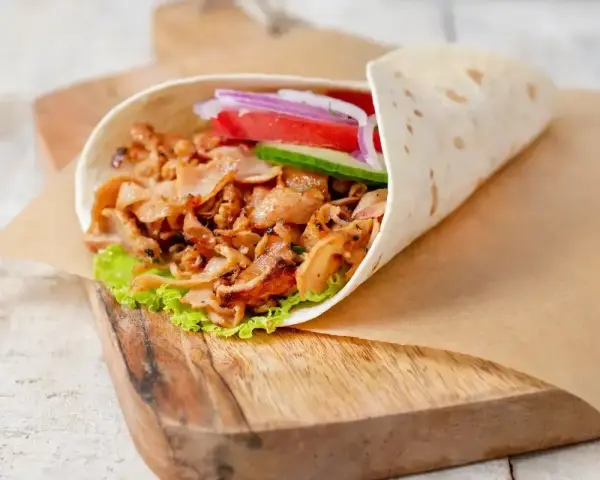 Pyszny kebab w picie z soczystym mięsem, świeżymi warzywami i chrupiącą sałatą, gotowy do zjedzenia.