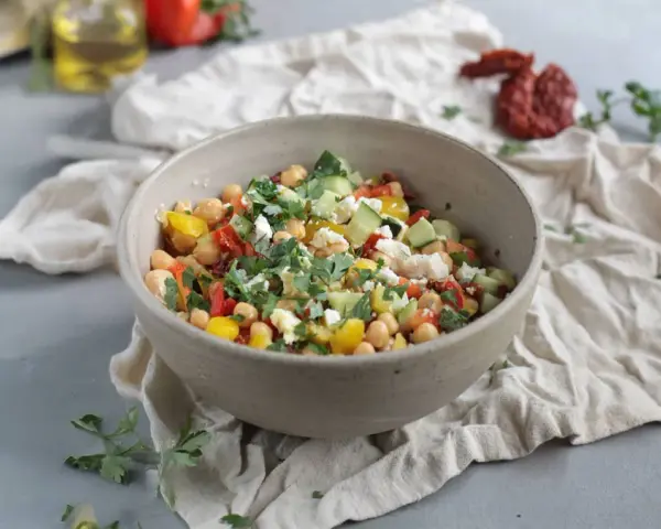 Ein bunter Kichererbsen Salat mit Gurken, Tomaten, Paprika und Feta, garniert mit frischer Petersilie.