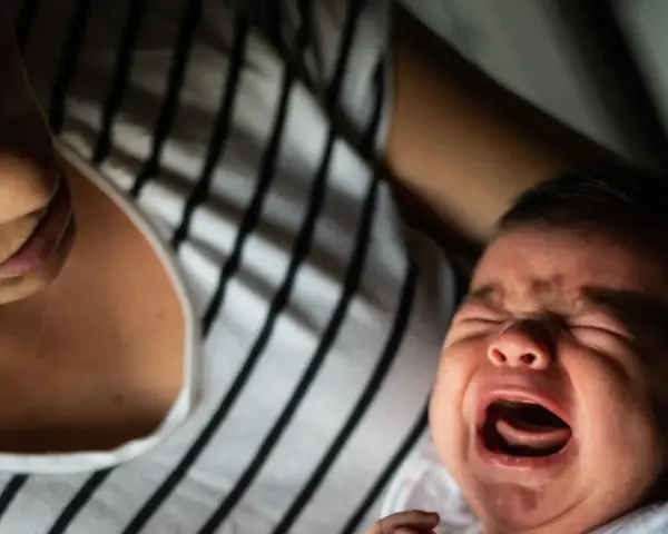 Ein schreiendes Baby, das von seiner Mutter getröstet wird. Vielleicht ein Zeichen für eine frühe Hochbegabung, die sich in intensiven Emotionen äußert.