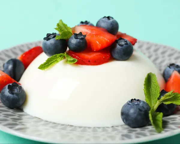 Szybkie ciasto z 4 składników: panna cotta z jagodami i truskawkami, ozdobiona miętą.