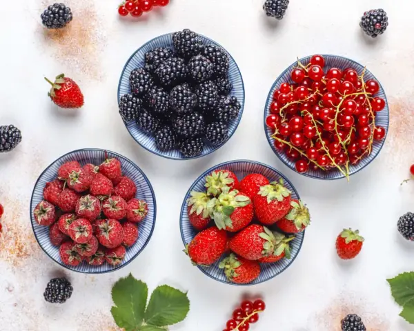 Miseczki z jeżynami, malinami, truskawkami i czerwonymi porzeczkami. Idealne owoce na keto, które dodadzą słodyczy bez wyrzutów sumienia.