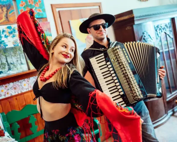 Zespół góralski disco polo w akcji! Wokalistka w barwnym stroju i akordeonista tworzą radosną atmosferę.