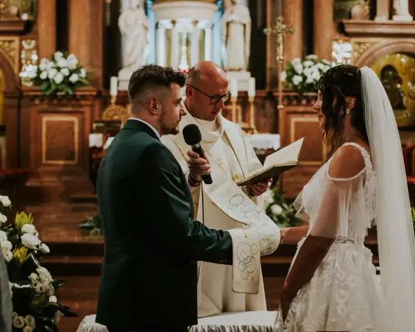 Para Młoda podczas uroczystości ślubu konkordatowego w kościele. Pan Młody w garniturze, Panna Młoda w sukni ślubnej.