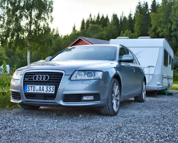 Grauer Audi A6 F4 Kombi mit Wohnwagen im Hintergrund, bereit für den Urlaub.