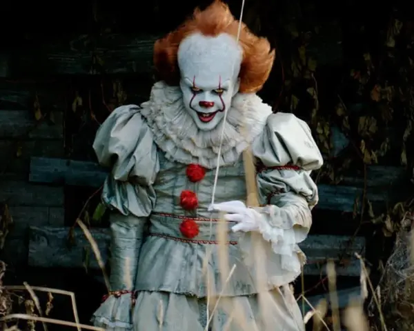 Przerażający klaun Pennywise, znany z horrorów Netflix, wychodzi z mroku.