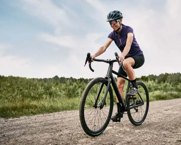 Kobieta na rowerze pokonuje szutrową drogę, wybierając trasę gravel czy cross.