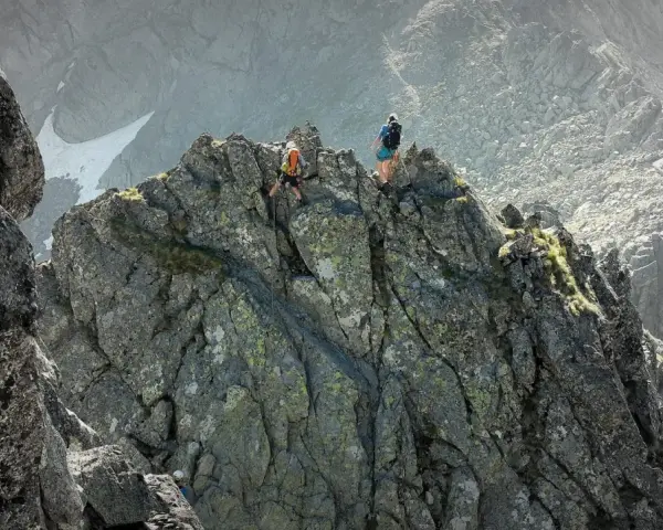 Dwóch alpinistów pokonuje skalisty grzbiet. Jeden z nich zjeżdża na linie, drugi czeka na szczycie. To trudna droga Martina na Gerlach.