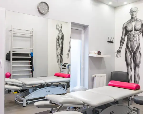 Gabinet rehabilitacyjny z leżankami, drabinką, piłką i aparaturą, w tym magnetronik na kolano.