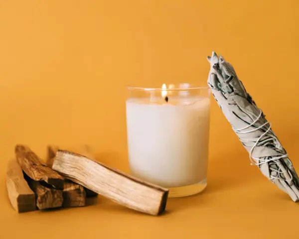 Palosanto, vela encendida y manojo de salvia. Prepara tu espacio para como quemar palo santo y purificar el ambiente.