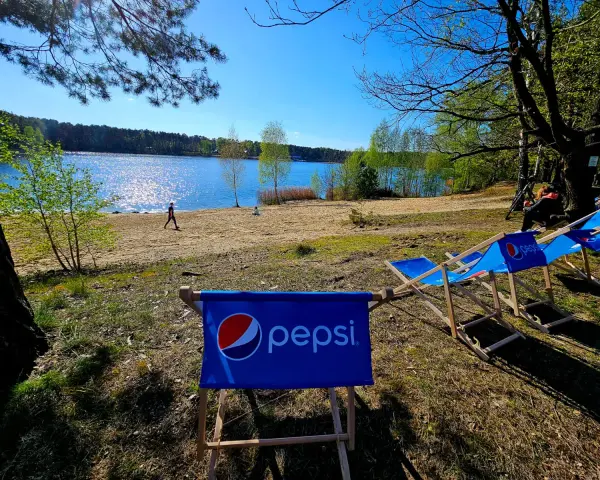 Słoneczny dzień nad jeziorem, leżaki z logo Pepsi czekają na gości turawa camp.