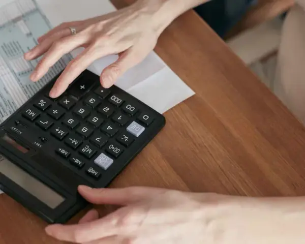 Manos calculando el total de suplidos en un formulario fiscal.