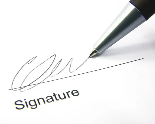 A pen signs a document, finalizing a corporate sponsorship agreement.
