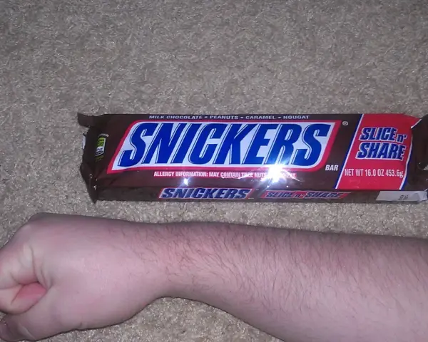 Ręka obok opakowania Snickersów. Zastanawiasz się nad snickers kcal?