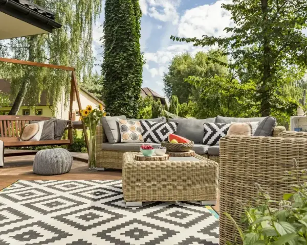 Relaks na tarasie w stylu boho: wiklinowe meble, huśtawka, wzorzysty dywan i mnóstwo zieleni.
